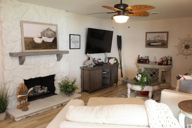 living room with ceiling fan, light wood-type flooring, and a fireplace