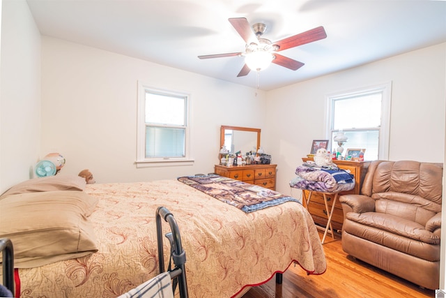 bedroom featuring multiple windows, hardwood / wood-style flooring, and ceiling fan