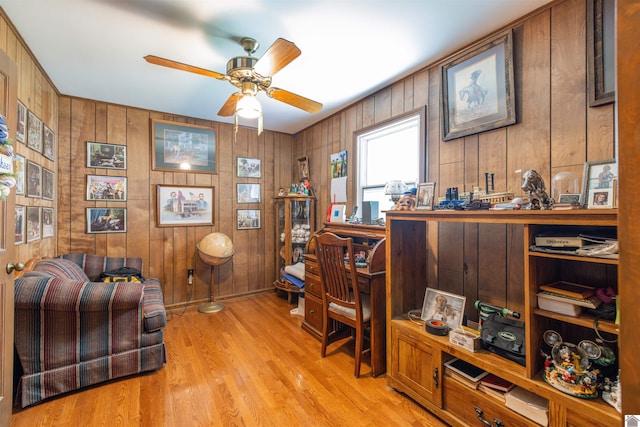 office space with wood walls, ceiling fan, and light wood-type flooring