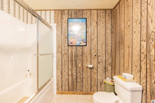 bathroom with shower / bath combination with glass door, toilet, a textured ceiling, and wooden walls