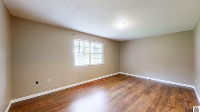 empty room with dark hardwood / wood-style floors and a textured ceiling