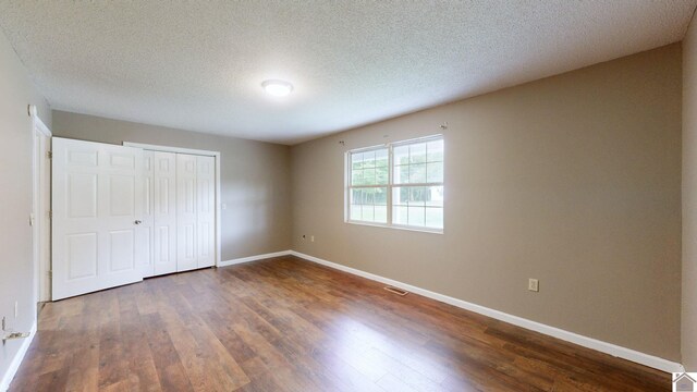 unfurnished bedroom with hardwood / wood-style flooring, a closet, and a textured ceiling