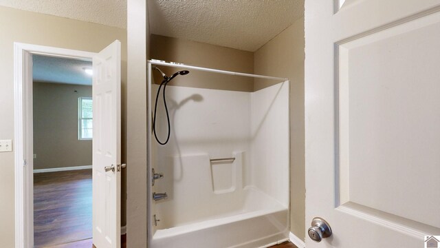 bathroom with bathing tub / shower combination, hardwood / wood-style floors, and a textured ceiling