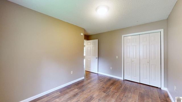 unfurnished bedroom featuring dark hardwood / wood-style floors, a textured ceiling, and a closet