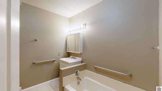 bathroom with tile patterned floors, vanity, a textured ceiling, and a tub to relax in