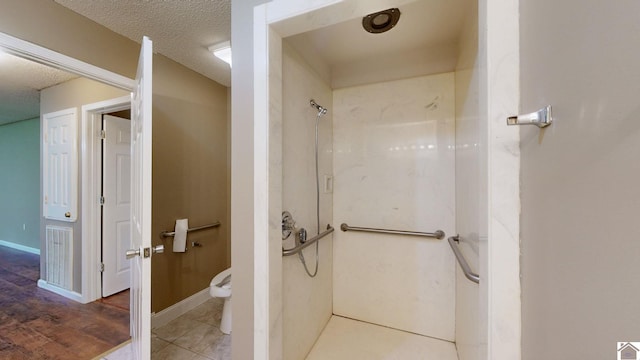 bathroom with tile patterned floors, toilet, a textured ceiling, and walk in shower