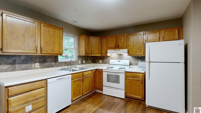 kitchen with decorative backsplash, dark hardwood / wood-style floors, white appliances, and sink