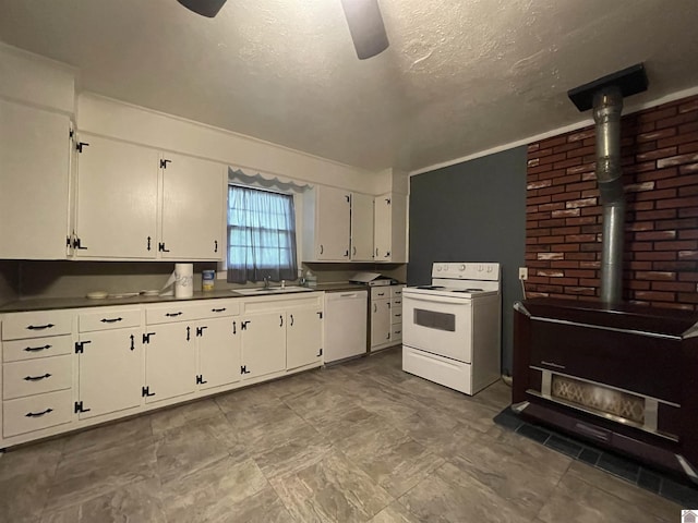 kitchen with white appliances, white cabinets, ceiling fan, a wood stove, and a sink