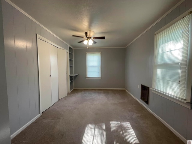 unfurnished bedroom with ornamental molding, carpet floors, and ceiling fan