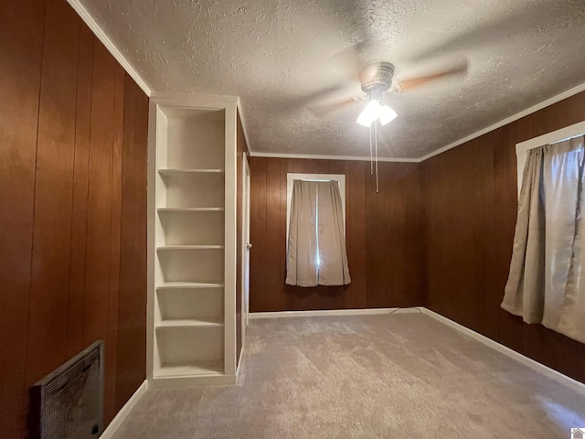 unfurnished bedroom featuring visible vents, crown molding, a textured ceiling, carpet flooring, and wood walls