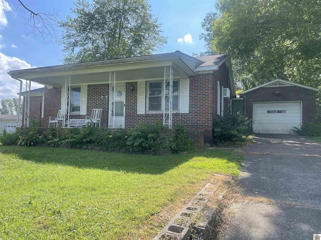 view of front of house featuring brick siding, a detached garage, covered porch, driveway, and a front lawn