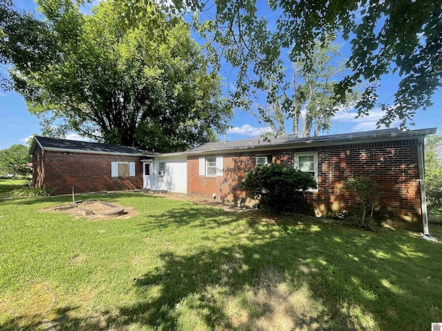 back of house with brick siding and a lawn