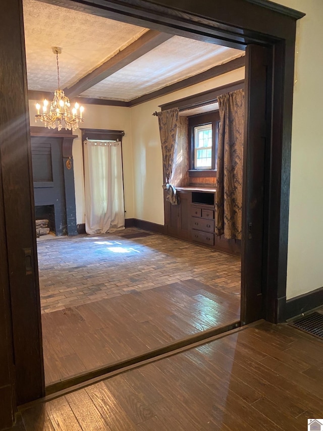 hallway featuring beamed ceiling, hardwood / wood-style flooring, crown molding, an inviting chandelier, and a textured ceiling