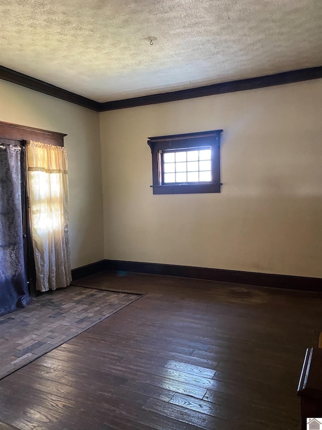 empty room with dark hardwood / wood-style flooring, ornamental molding, and a textured ceiling