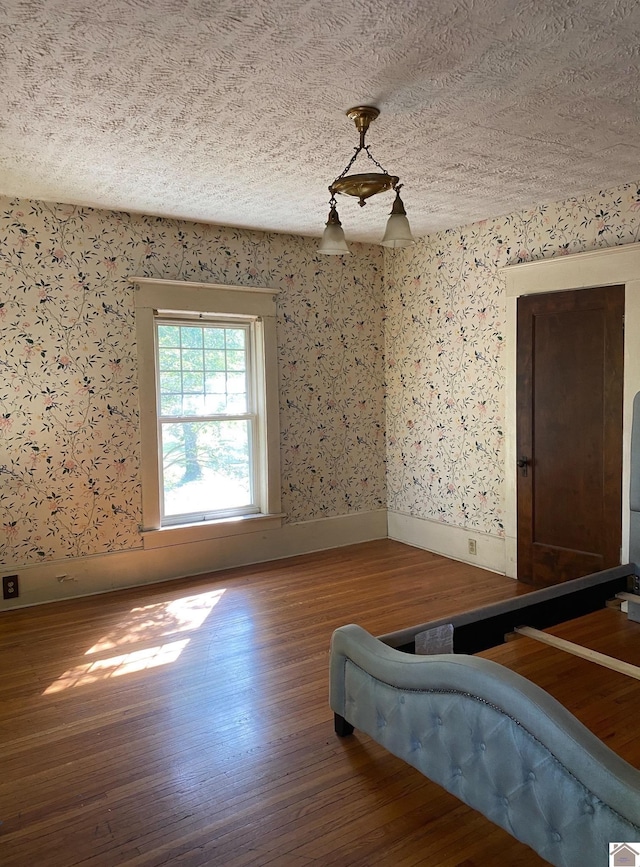 empty room featuring wood-type flooring and a textured ceiling