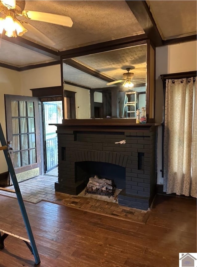 unfurnished living room with a brick fireplace, ceiling fan, wood-type flooring, and a textured ceiling