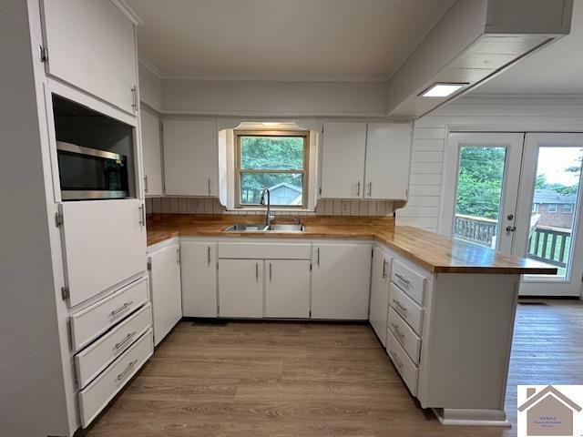 kitchen featuring sink, light hardwood / wood-style floors, white cabinets, french doors, and kitchen peninsula