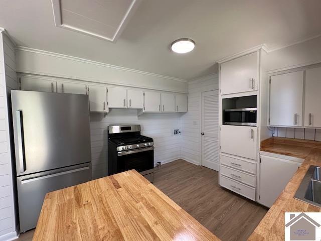 kitchen with dark wood-type flooring, white cabinetry, stainless steel appliances, and butcher block countertops