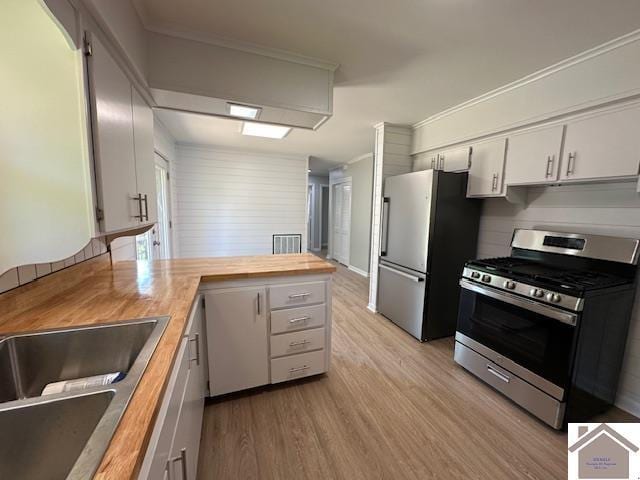 kitchen with butcher block countertops, sink, white cabinets, stainless steel appliances, and light wood-type flooring