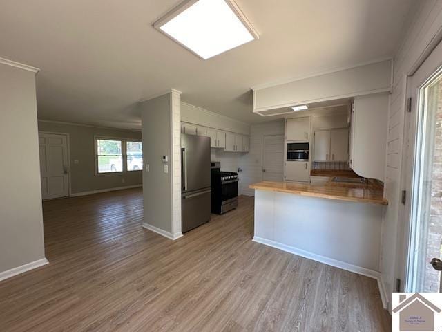 kitchen with hardwood / wood-style floors, white cabinetry, kitchen peninsula, stainless steel appliances, and crown molding