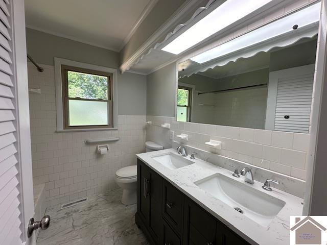 bathroom with ornamental molding, vanity, toilet, and tile walls