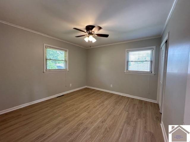 empty room featuring crown molding, wood-type flooring, and ceiling fan