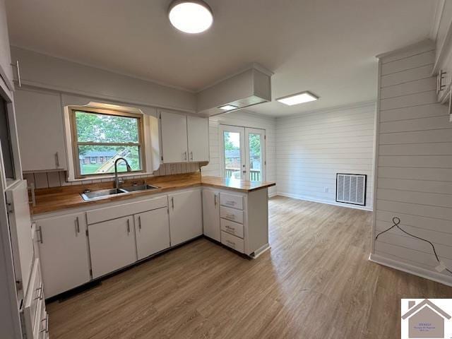 kitchen with white cabinetry, kitchen peninsula, light hardwood / wood-style flooring, and french doors