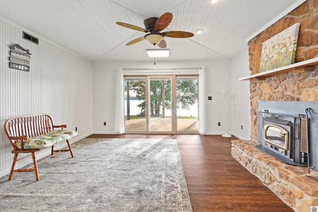 sitting room with hardwood / wood-style flooring, a wood stove, a fireplace, and ceiling fan