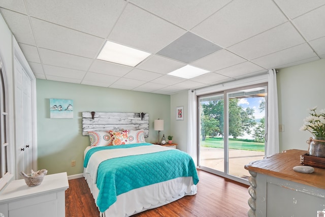 bedroom with a paneled ceiling, wood-type flooring, and access to outside