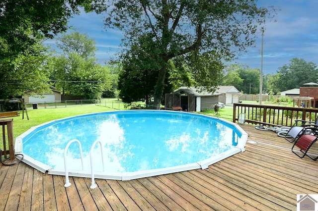 view of swimming pool with a lawn, a deck, and a shed