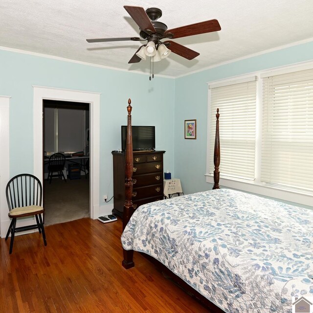 bedroom with a spacious closet, a closet, hardwood / wood-style floors, crown molding, and ceiling fan