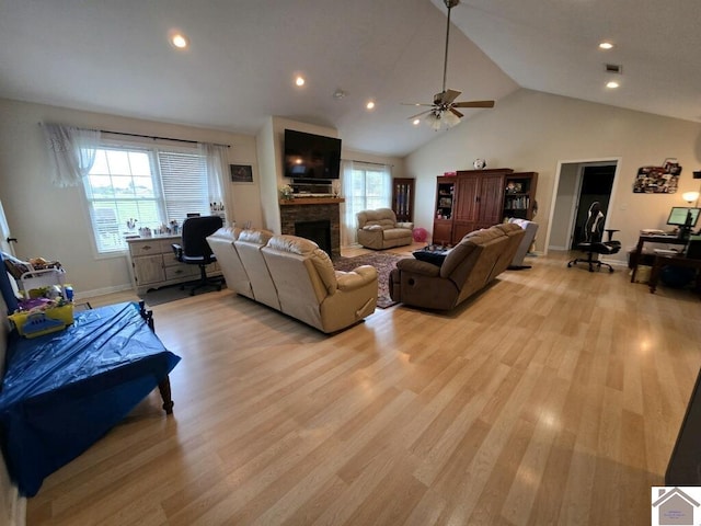 living room featuring light hardwood / wood-style flooring, a fireplace, ceiling fan, and plenty of natural light