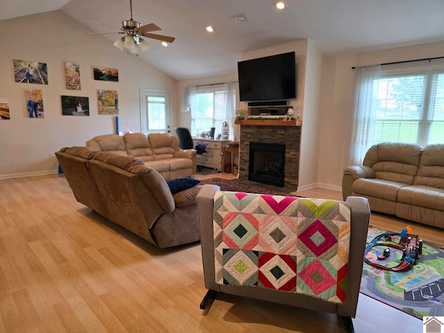 living room featuring a fireplace, light hardwood / wood-style floors, vaulted ceiling, and a wealth of natural light