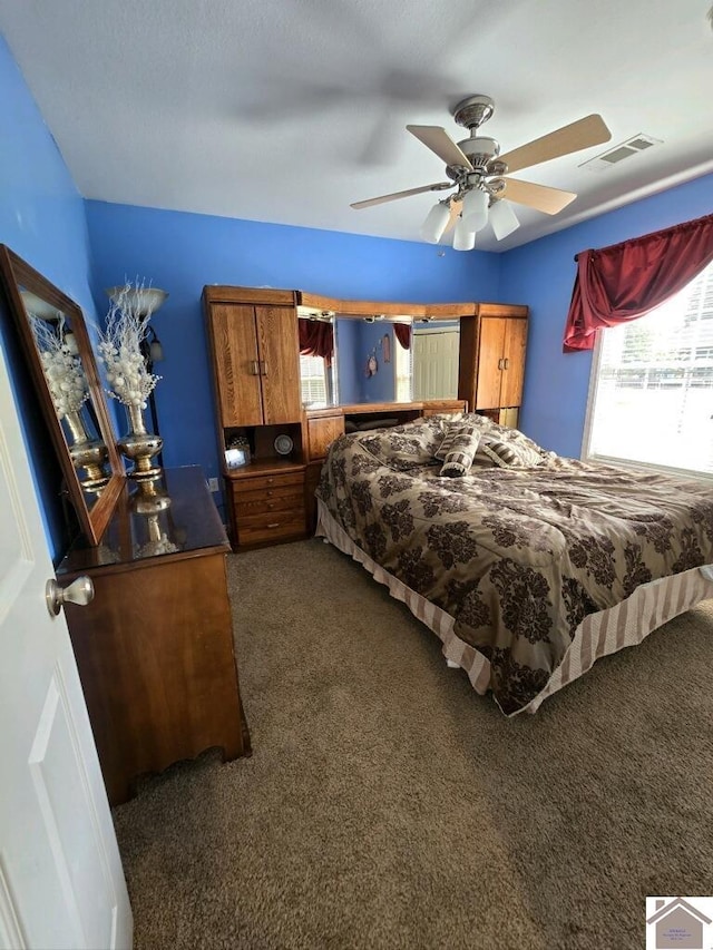 carpeted bedroom with multiple windows and ceiling fan