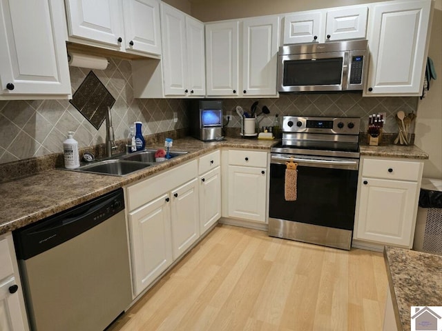 kitchen with white cabinetry, decorative backsplash, light wood-type flooring, and stainless steel appliances