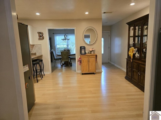 interior space with light wood-type flooring, backsplash, and a breakfast bar