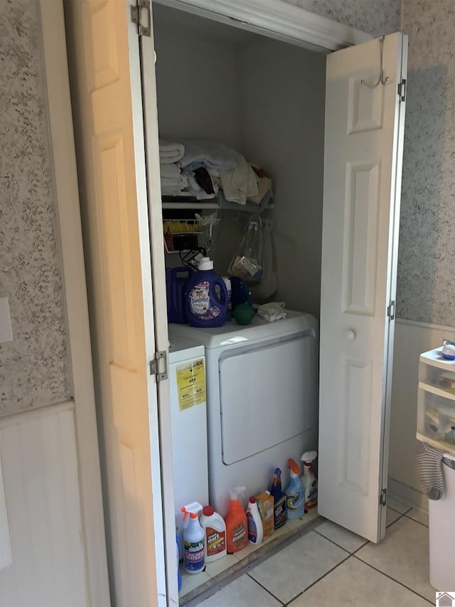 washroom with a barn door, light tile patterned flooring, and separate washer and dryer