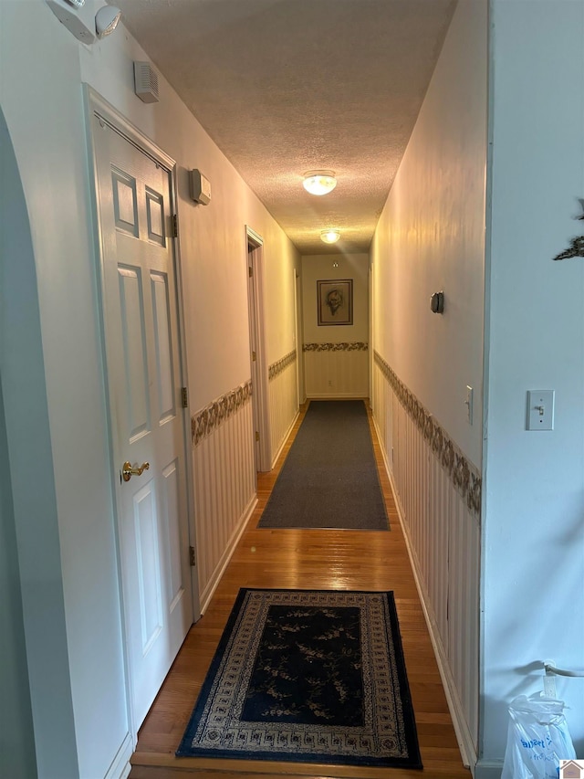 hall with a textured ceiling and dark wood-type flooring