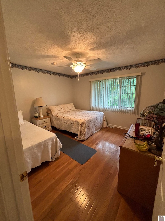 bedroom featuring hardwood / wood-style flooring, a textured ceiling, and ceiling fan