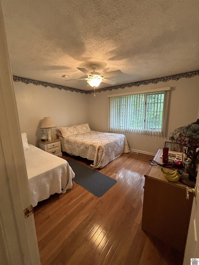 bedroom featuring hardwood / wood-style flooring, a textured ceiling, and ceiling fan