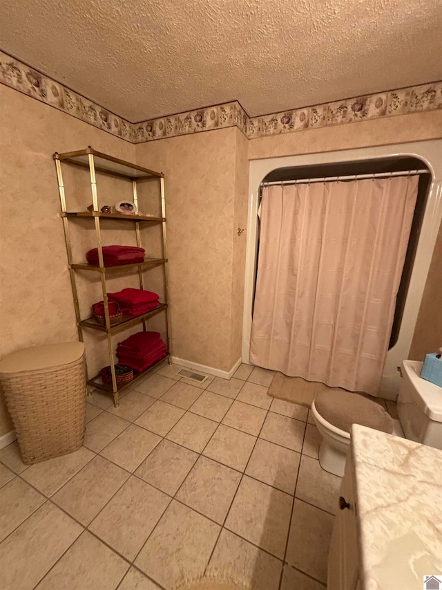 bathroom with tile patterned floors, toilet, and a textured ceiling