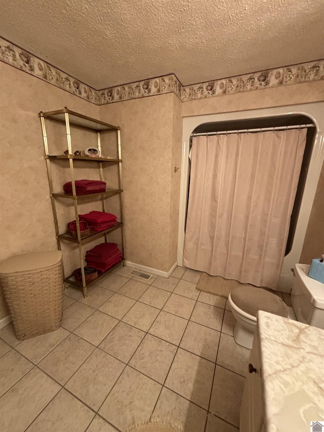 bathroom with vanity, toilet, tile patterned flooring, and a textured ceiling