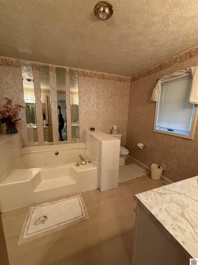 bathroom with vanity, a tub, a textured ceiling, and toilet