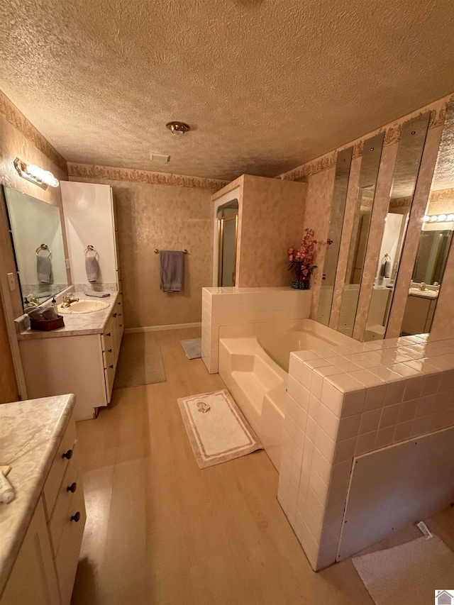 bathroom with vanity, a textured ceiling, and a bathtub