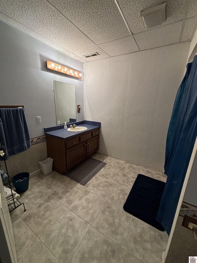 bathroom with vanity, tile patterned flooring, and a drop ceiling