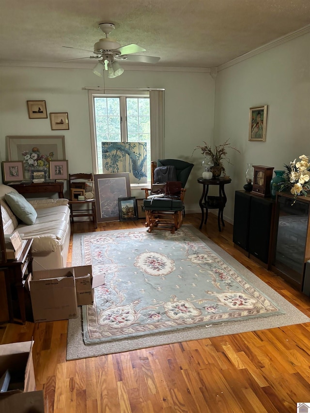 living room with crown molding, ceiling fan, and light hardwood / wood-style floors