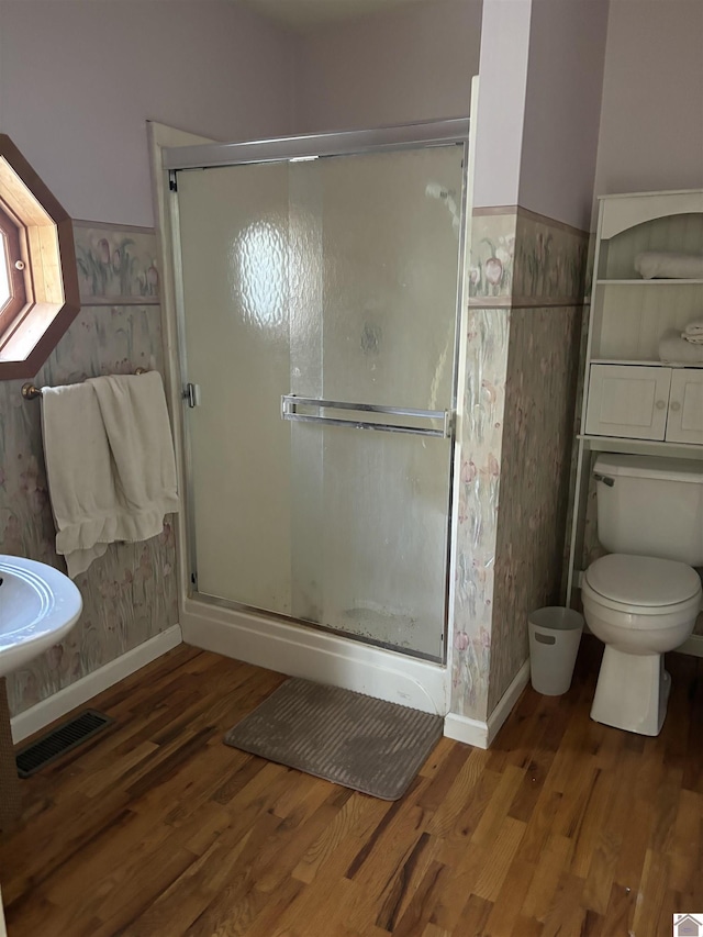 bathroom featuring hardwood / wood-style floors, a shower with shower door, and toilet