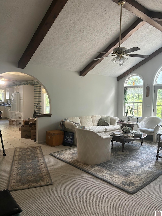 carpeted living room featuring lofted ceiling with beams, a textured ceiling, and ceiling fan