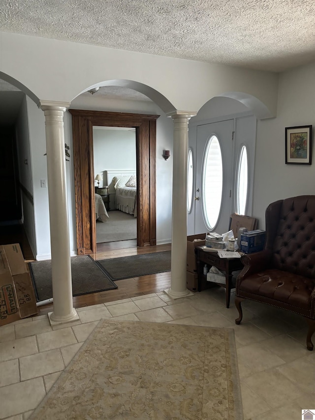 entrance foyer featuring ornate columns and a textured ceiling