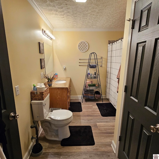 bathroom featuring ornamental molding, vanity, a textured ceiling, wood-type flooring, and toilet